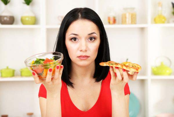A Young Woman holding a bowl of salad and a pizza