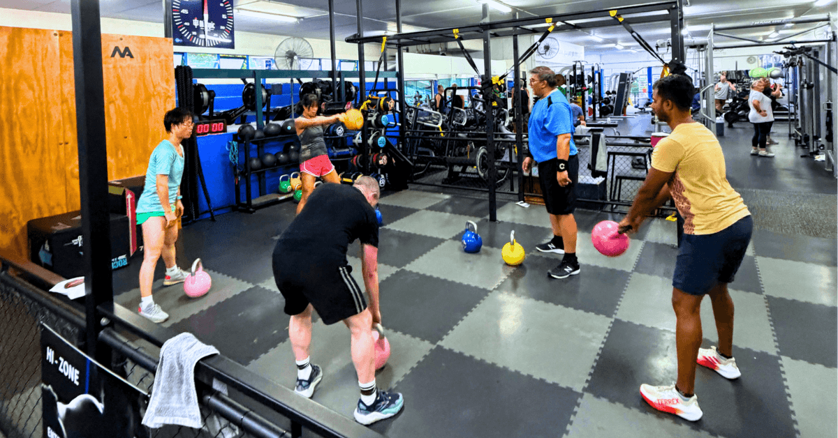 Personal trainer guiding member through exercise program at The Olympic